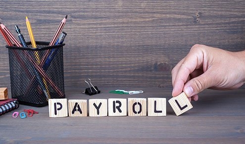 payroll. Wooden letters on dark background